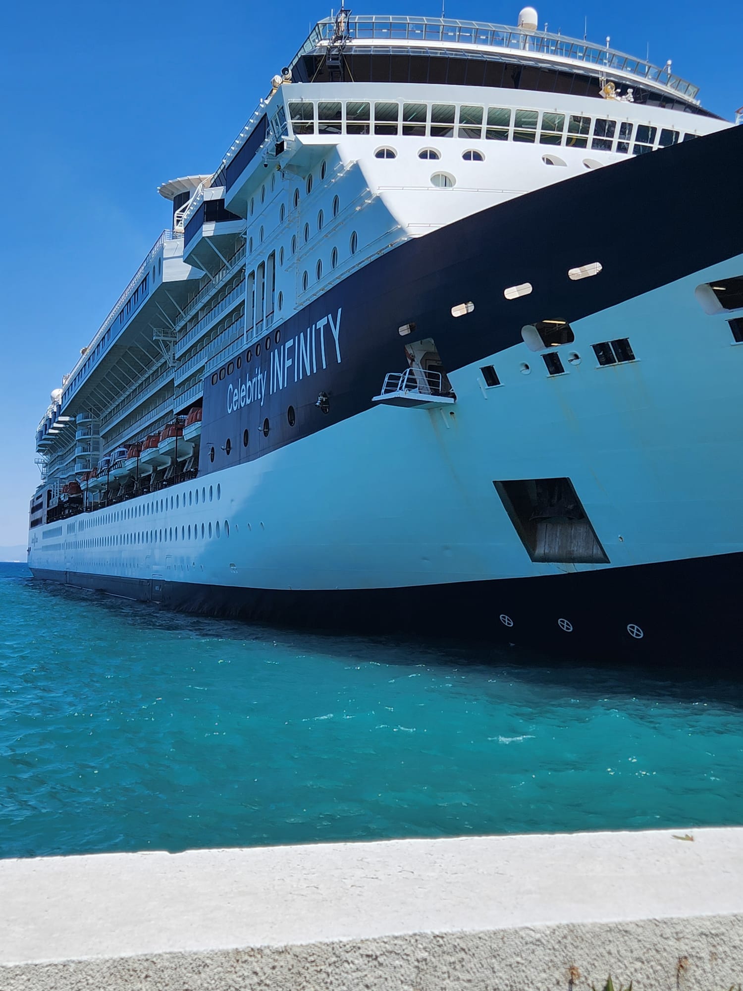A cruise ship moored in clear turquoise water on a bright day